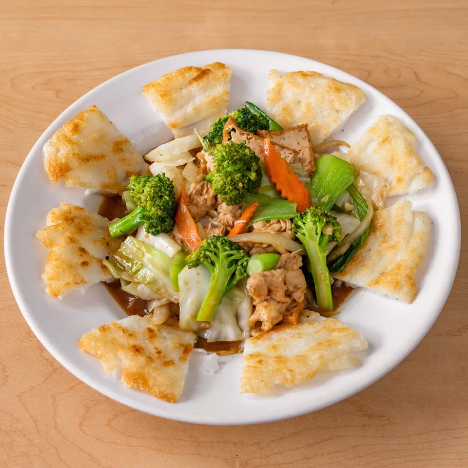 Happy Veggie's vegan stir-fry with broccoli, carrots, cabbage, and tofu, surrounded by crispy flatbread pieces.